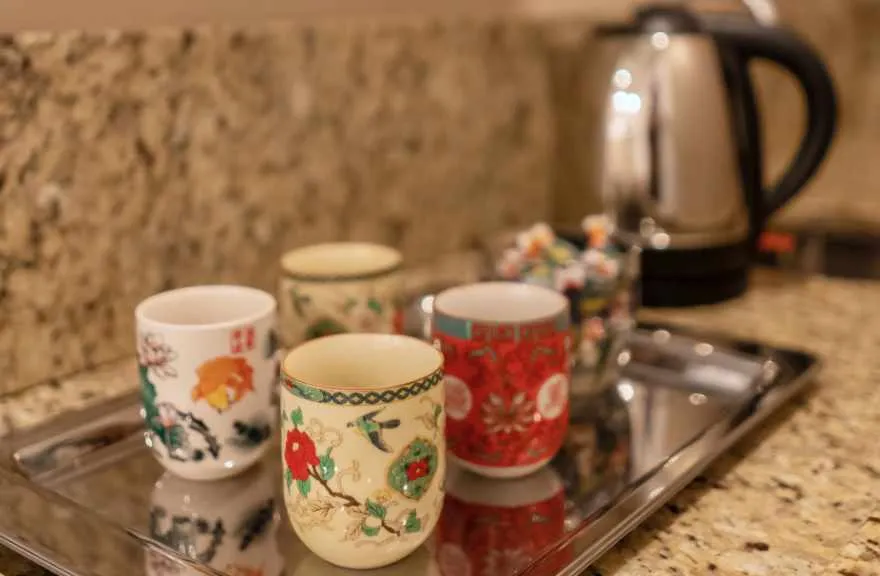 Xícaras de porcelana e chaleira sobre a bandeja